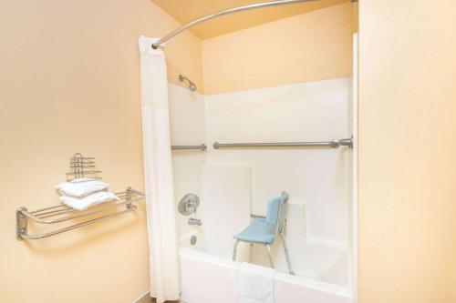 a bathroom with a shower with a blue chair in it at Travelodge by Wyndham Kingman in Kingman