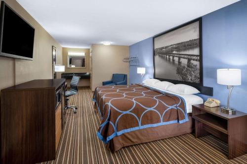 a hotel room with a bed and a flat screen tv at Super 8 by Wyndham Gadsden AL in Gadsden