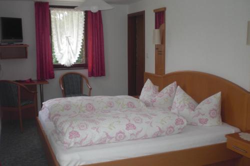 a bedroom with a bed with pink sheets and pillows at Gasthaus Pension Donishäusle in Titisee-Neustadt