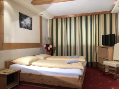 a bedroom with a large bed and a television at Ferienhof Kampfl in Fügen