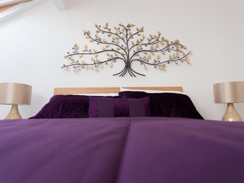 Luxurious Serviced Apartments في ليدز: غرفة نوم بسرير ارجواني مع مصباحين