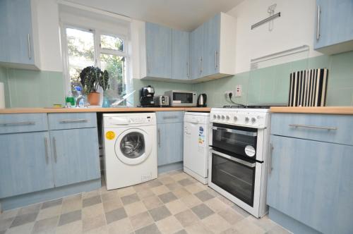 a kitchen with blue cabinets and a washing machine at Large Garden flat in the heart of Islington in London
