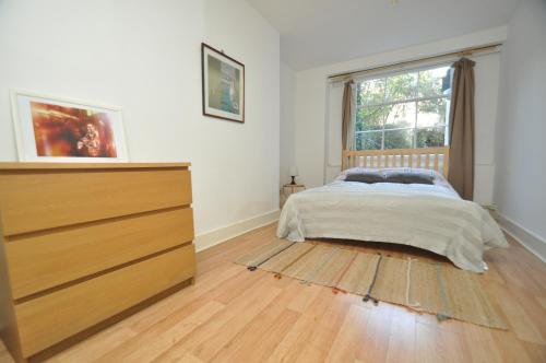 a bedroom with a bed and a dresser and a window at Large Garden flat in the heart of Islington in London