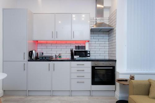 uma cozinha com armários brancos e um micro-ondas em The Avenue Apartments em Leeds