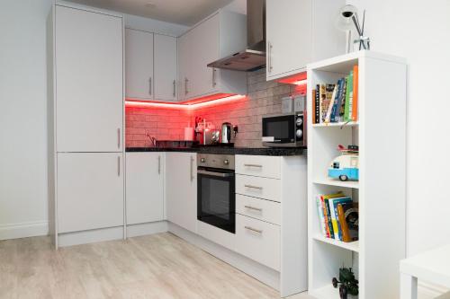 a kitchen with white cabinets and a red brick wall at The Avenue Apartments in Leeds