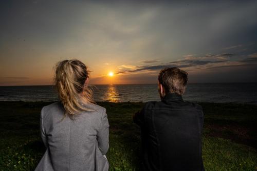 a man and a woman looking at the sunset at Grand Hotel Beatrix in Den Helder
