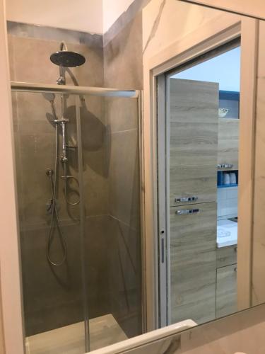 La salle de bains est pourvue d'une douche avec une porte en verre. dans l'établissement Salinis Apartments, à Margherita di Savoia