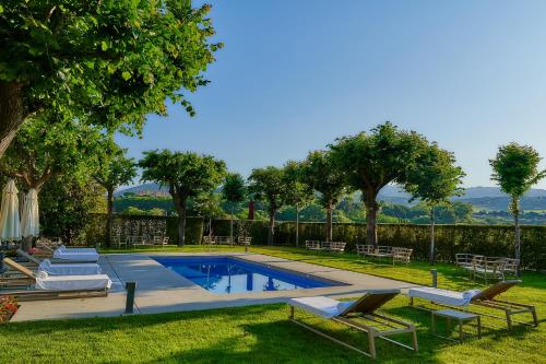 a park with a pool, lawn chairs, and trees at Hotel Arrey Alella in Alella
