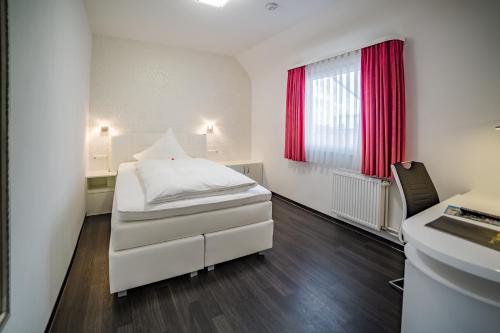 
a bedroom with a white bed and white walls at Hotel Linde in Donaueschingen
