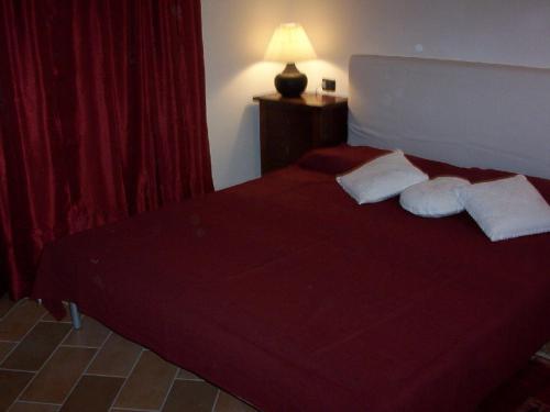 a bedroom with a red bed with two pillows at Il Portico in Carrosio