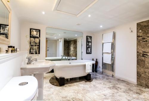 a bathroom with a tub and a toilet and a sink at The Crown Inn in Peterborough