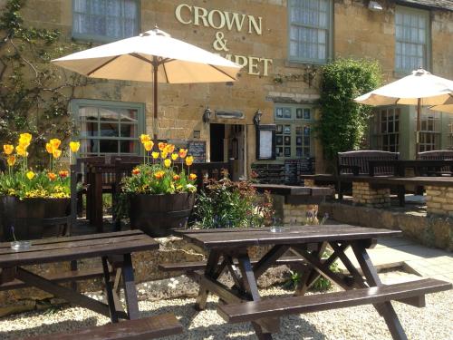 twee picknicktafels met parasols voor een gebouw bij Crown and Trumpet Inn in Broadway