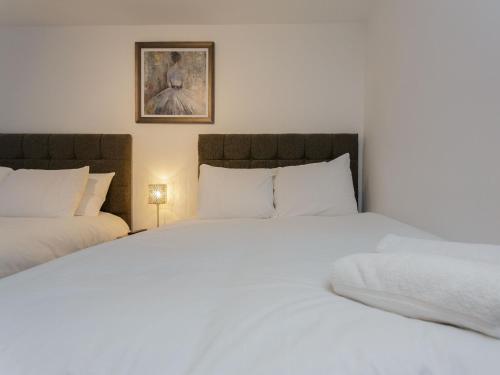 een slaapkamer met twee witte bedden en een foto aan de muur bij Live in Leeds Greenhill Bungalows in Leeds