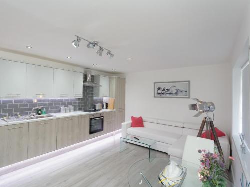 a living room with a white couch and a kitchen at Live in Leeds Greenhill Bungalows in Leeds
