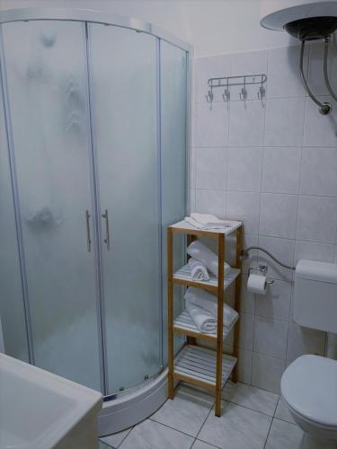 a bathroom with a shower and a toilet and towels at Apartmani Strada in Kaštela