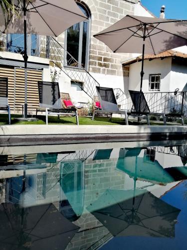 a swimming pool with two chairs and an umbrella at La Maison Grivolas Appartements et Maison d'hôtes in Avignon