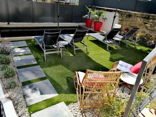 a patio with chairs and a table and grass at La Maison Grivolas Appartements et Maison d'hôtes in Avignon