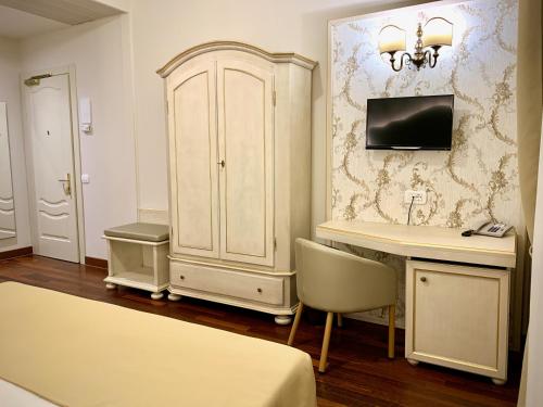 a bedroom with a desk and a cabinet and a tv at Albergo Gardesana in Torri del Benaco
