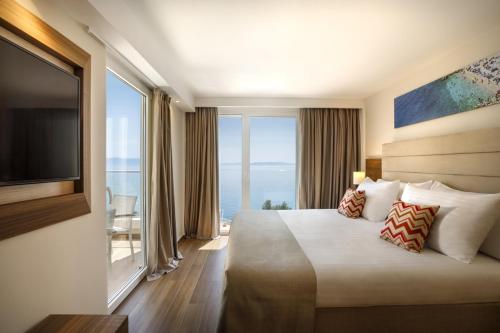 a hotel room with a bed and a large window at Girandella Resort, Valamar Collection in Rabac