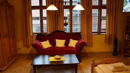 sala de estar con sofá rojo y almohadas amarillas en Gästehaus am Wasserturm, en Lüneburg