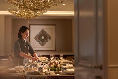 a woman standing in front of a table with wine glasses at InterContinental Singapore by IHG in Singapore