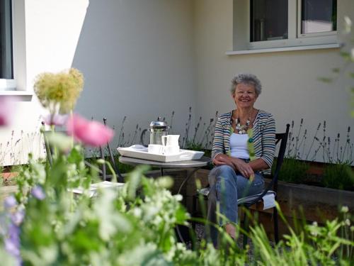 
a woman sitting in front of a garden with flowers at Hale House in Wendover
