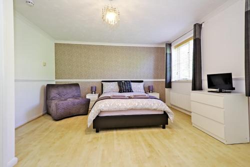 a bedroom with a bed, chair, and a window at Harlinger Lodge Annexe in London