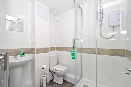 a white bathroom with a shower and a toilet at Harlinger Lodge Annexe in London