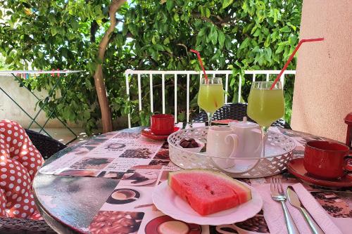 a table with a plate of watermelon and two glasses of juice at Apartments Roso - ZF Hvar in Hvar