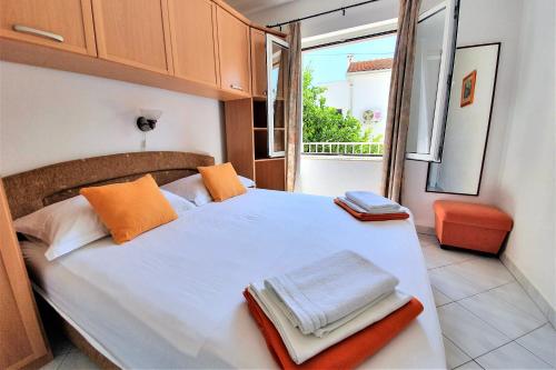 a bedroom with a white bed with orange towels on it at Apartments Roso - ZF Hvar in Hvar