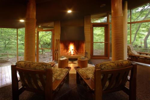 a living room with two chairs and a fireplace at Bettei Senjyuan in Minakami