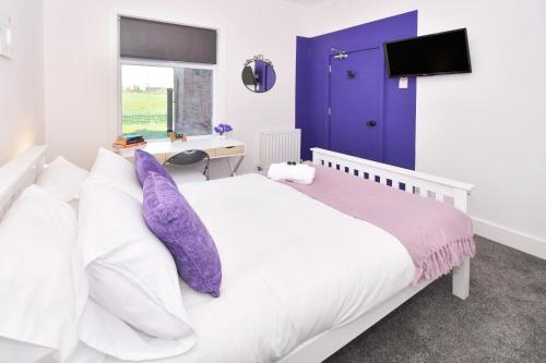 a bedroom with a white bed with purple pillows at Townhouse @ Henry Street Crewe in Crewe
