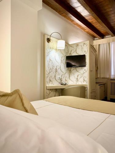 a white bedroom with a bed and a wall at Albergo Gardesana in Torri del Benaco