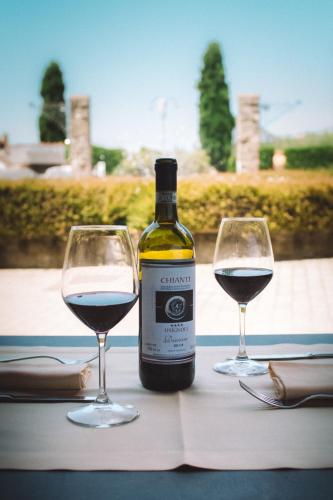 a bottle of wine and two glasses on a table at Fattoria Degli Usignoli in San Donato in Fronzano