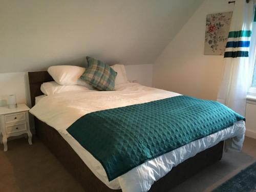 a bed with a green and white comforter in a bedroom at Hillside in Kyleakin