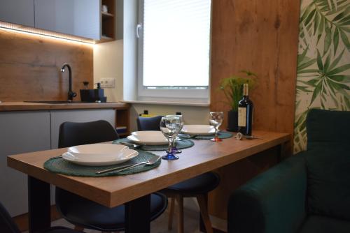 una mesa de madera con platos y copas de vino. en Apartament RESTO, en Świeradów-Zdrój