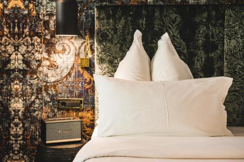 a bedroom with a bed with white pillows and a wall at Alpin Garden Luxury Maison & SPA - Adults Only in Ortisei