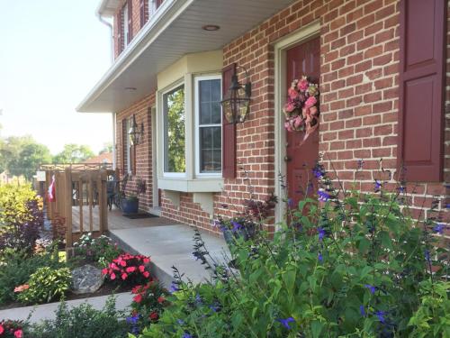 a brick house with a red door and flowers at Homestead Lodging in Smoketown