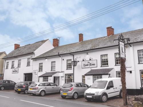 um edifício branco com carros estacionados em frente em The Hood Arms em Kilve