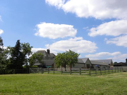 a house in a field with a fence at Hook Farm Cottages in Royal Wootton Bassett