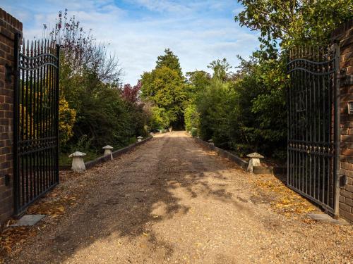 a dirt road with a gate and trees at Hookwood Lodge in Horley