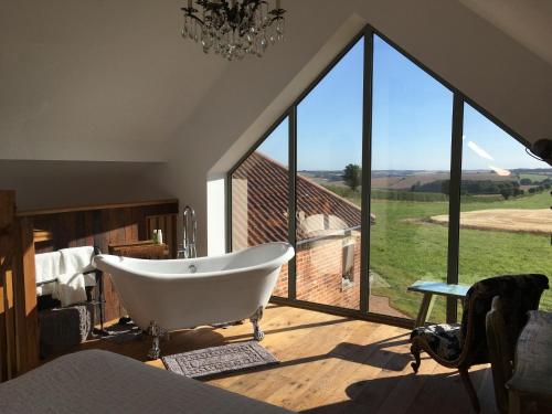a bathroom with a tub and a large window at Horizon Barn in Market Rasen