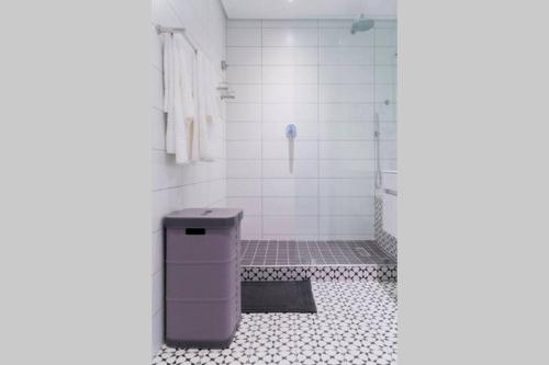 a bathroom with a shower and a trash can at Waterfront Getaway, 2 Bedroom Seaside Bliss in Umdloti