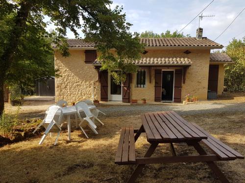 a picnic table and chairs in front of a house at Petite maison du Tertre in Baneuil