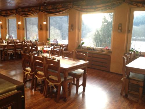 a dining room with tables and chairs and windows at Hotel Forsthaus in Volkesfeld