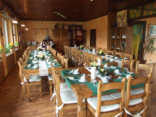 una lunga sala da pranzo con tavoli e sedie lunghi di Hotel Forsthaus a Volkesfeld