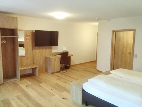 Habitación con cama, escritorio y TV. en Hotel Gasthof Zum Löwen, en Velburg