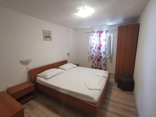 a small bedroom with a bed and a window at Apartmani Franceska in Bol