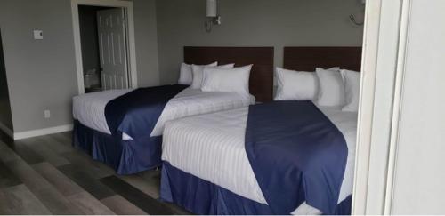 two beds in a hotel room with two at Hotel-Motel Fleur de Lys in Perce
