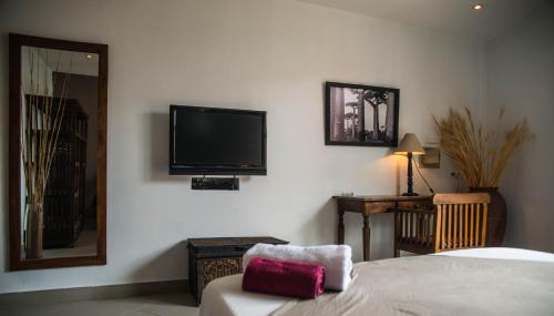 a hotel room with a bed, television and a painting on the wall at Hôtel Restaurant La Ribaudière in Antananarivo